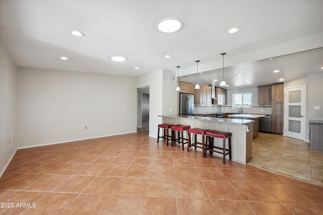 kitchen featuring appliances with stainless steel finishes, a breakfast bar, decorative light fixtures, light tile patterned floors, and kitchen peninsula