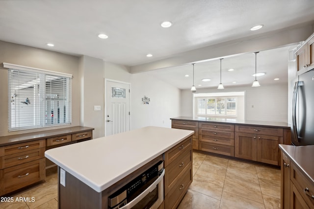 kitchen with hanging light fixtures, light tile patterned flooring, a kitchen island, and stainless steel appliances