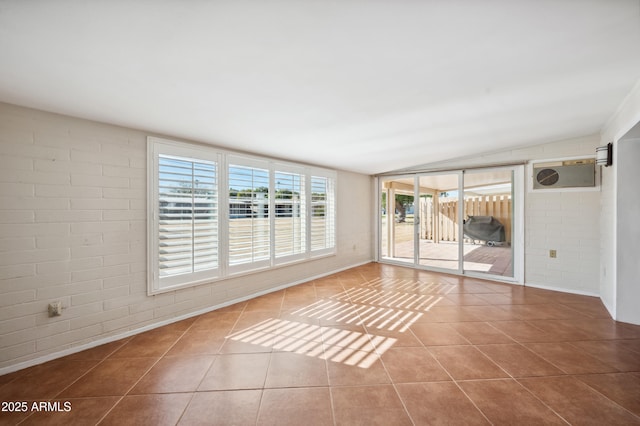 tiled empty room featuring vaulted ceiling