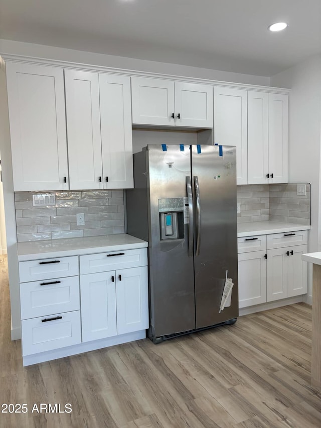 3627 W Palmaire Ave, Phoenix, AZ 85051 - kitchen with stainless steel fridge, light countertops, backsplash, light wood-style flooring, and white cabinets