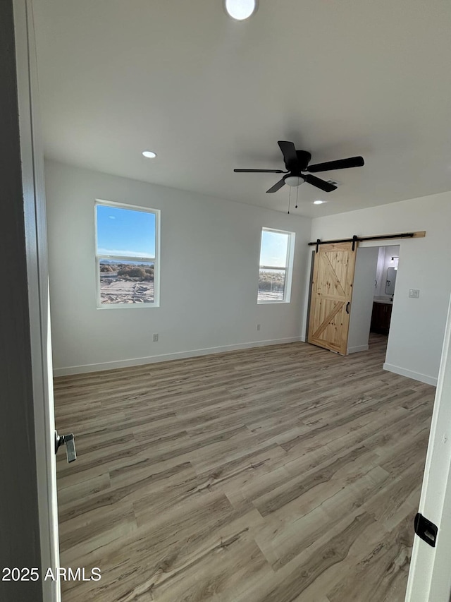 3627 W Palmaire Ave, Phoenix, AZ 85051 - unfurnished bedroom featuring light wood finished floors, a barn door, recessed lighting, baseboards, and ceiling fan