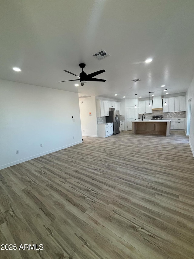 3627 W Palmaire Ave, Phoenix, AZ 85051 - unfurnished living room with light wood finished floors, recessed lighting, baseboards, a ceiling fan, and a sink