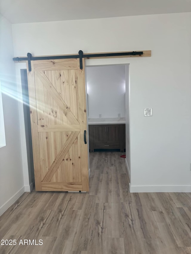 3627 W Palmaire Ave, Phoenix, AZ 85051 - hallway with a barn door, wood finished floors, and baseboards