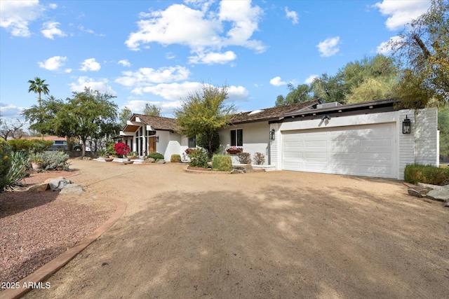 single story home featuring driveway, an attached garage, and stucco siding