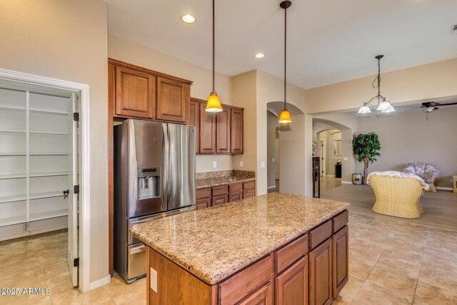 16758 W Apache St, Goodyear, AZ 85338 - kitchen with stainless steel fridge, arched walkways, ceiling fan, a center island, and open floor plan