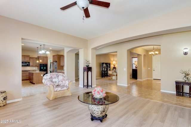 16758 W Apache St, Goodyear, AZ 85338 - living room featuring arched walkways, light wood finished floors, a ceiling fan, and a chandelier
