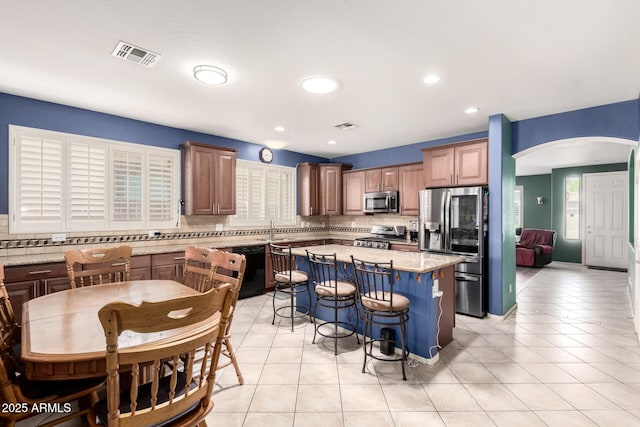 81 E Rock Wren Dr, San Tan Valley, AZ 85143 - kitchen with stainless steel appliances, arched walkways, backsplash, a sink, and a kitchen breakfast bar