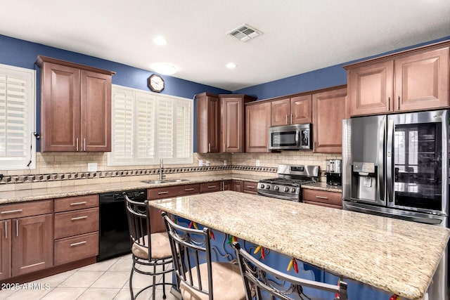 81 E Rock Wren Dr, San Tan Valley, AZ 85143 - kitchen featuring stainless steel appliances, a sink, backsplash, light stone countertops, and a kitchen bar