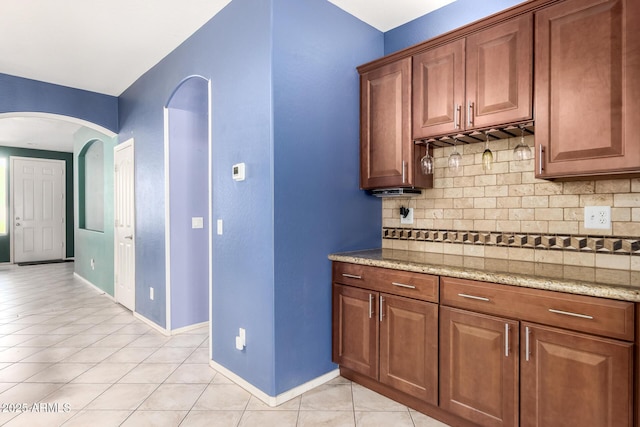 81 E Rock Wren Dr, San Tan Valley, AZ 85143 - kitchen with arched walkways, light tile patterned floors, tasteful backsplash, baseboards, and light stone countertops