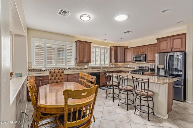 81 E Rock Wren Dr, San Tan Valley, AZ 85143 - kitchen with appliances with stainless steel finishes, a breakfast bar area, tasteful backsplash, a kitchen island, and light tile patterned floors
