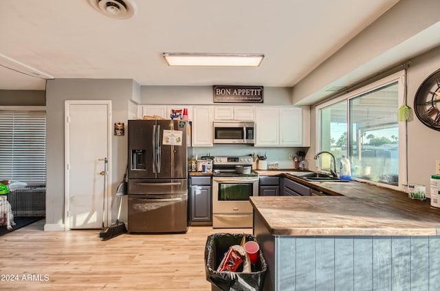 13802 N 37th Dr, Phoenix, AZ 85053 - kitchen featuring stainless steel appliances, white cabinets, light wood-style floors, a peninsula, and gray cabinets