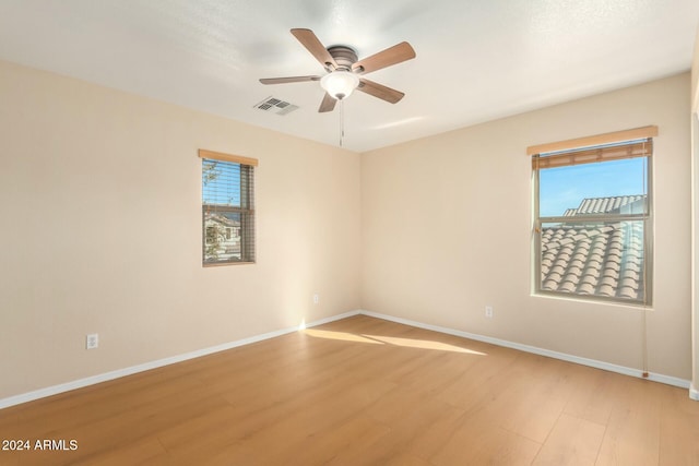 empty room featuring ceiling fan, plenty of natural light, and light hardwood / wood-style flooring