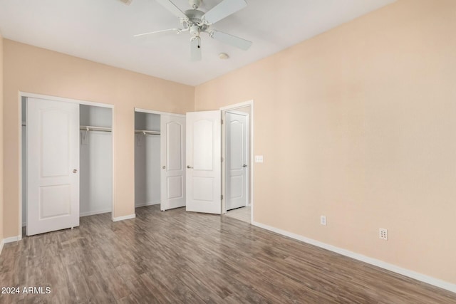 unfurnished bedroom featuring two closets, hardwood / wood-style flooring, and ceiling fan