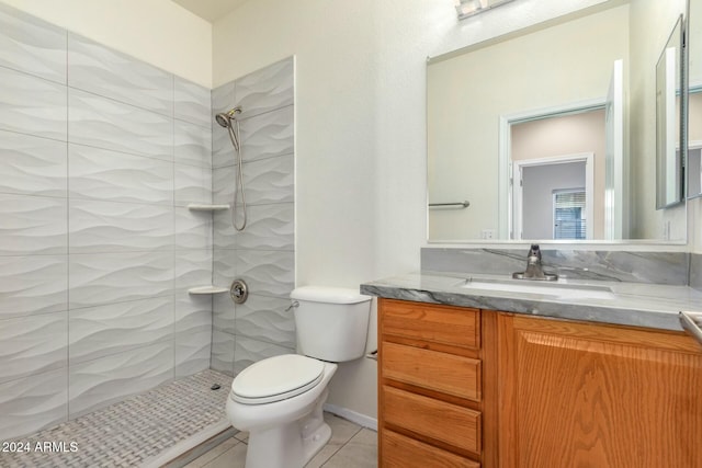 bathroom with tiled shower, vanity, tile patterned floors, and toilet