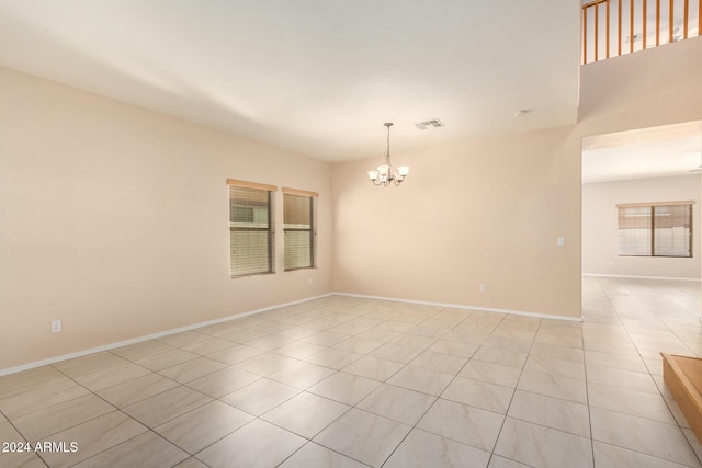 tiled empty room with an inviting chandelier