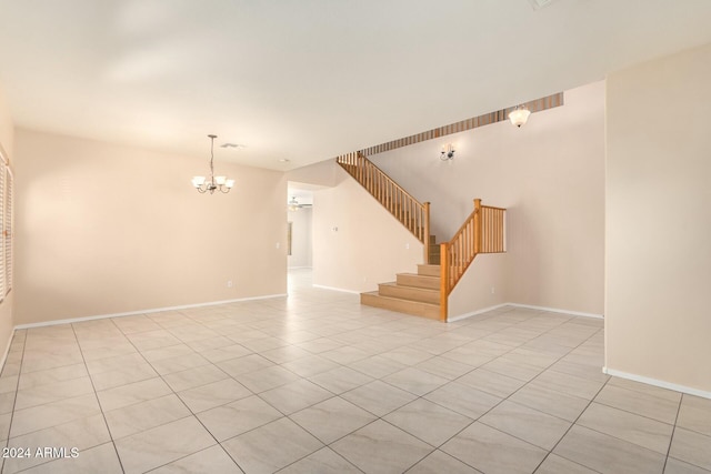 tiled empty room featuring a chandelier