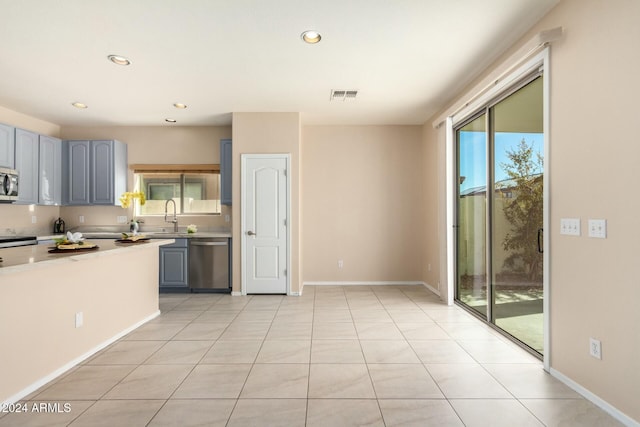 kitchen with light tile patterned floors, stainless steel appliances, and gray cabinetry