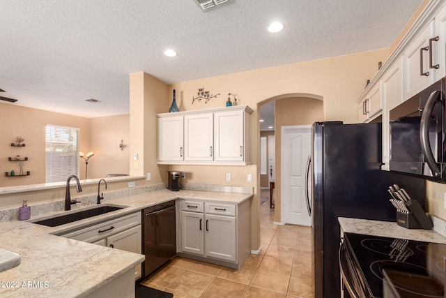 kitchen featuring sink, black appliances, light stone countertops, white cabinets, and light tile patterned flooring