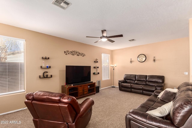 carpeted living room with a textured ceiling and ceiling fan