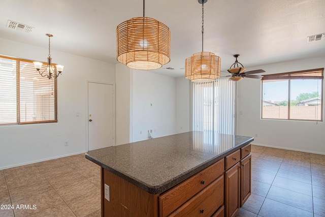 kitchen with a kitchen island, decorative light fixtures, dark stone counters, light tile patterned floors, and ceiling fan