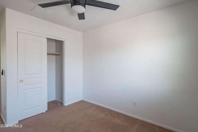 unfurnished bedroom with light colored carpet, a closet, and ceiling fan