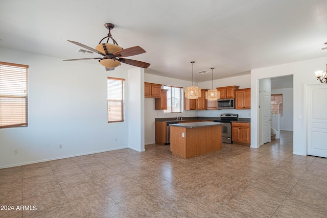 kitchen featuring ceiling fan with notable chandelier, stainless steel appliances, hanging light fixtures, and a kitchen island