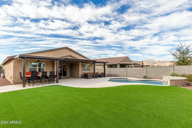 rear view of property featuring a fenced in pool, a patio area, and a lawn