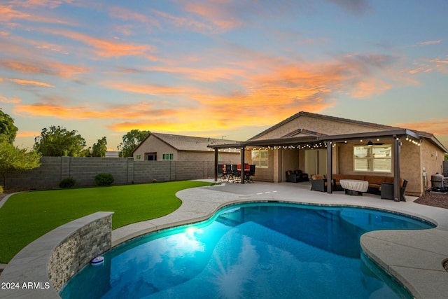 pool at dusk with a yard and a patio