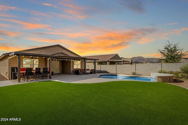 back house at dusk with a fenced in pool, a yard, and a patio