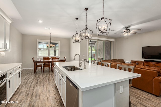 kitchen with a kitchen island with sink, sink, dishwasher, and white cabinets