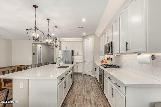 kitchen with appliances with stainless steel finishes, pendant lighting, white cabinetry, a kitchen bar, and a large island