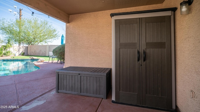 property entrance with a fenced in pool, a patio, fence, and stucco siding