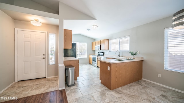 kitchen with lofted ceiling, stainless steel appliances, a peninsula, baseboards, and light countertops