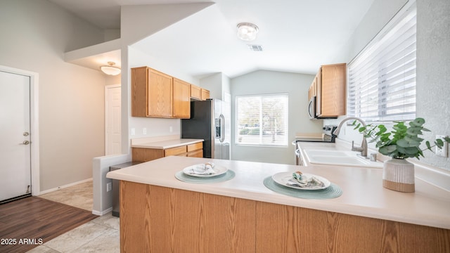 kitchen featuring visible vents, appliances with stainless steel finishes, a peninsula, vaulted ceiling, and a sink