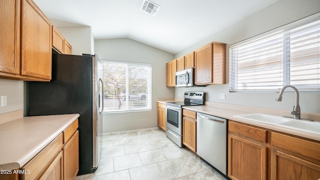 kitchen featuring lofted ceiling, a sink, visible vents, light countertops, and appliances with stainless steel finishes