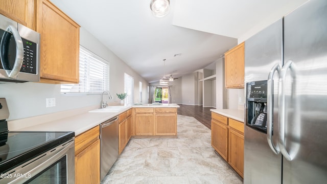 kitchen featuring lofted ceiling, appliances with stainless steel finishes, a peninsula, light countertops, and a sink