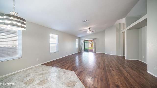 unfurnished room with baseboards, visible vents, wood finished floors, vaulted ceiling, and ceiling fan with notable chandelier