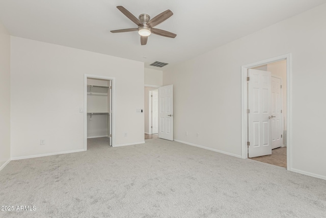 unfurnished bedroom with light carpet, a spacious closet, and ceiling fan