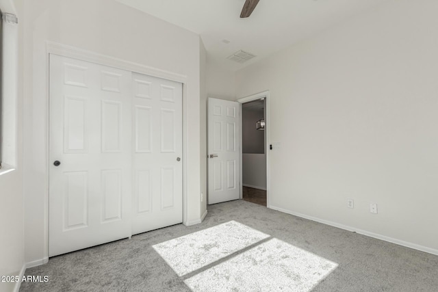 unfurnished bedroom featuring ceiling fan, a closet, and light colored carpet