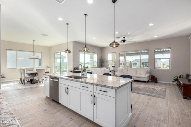 kitchen with light stone countertops, stainless steel dishwasher, ceiling fan, sink, and white cabinetry