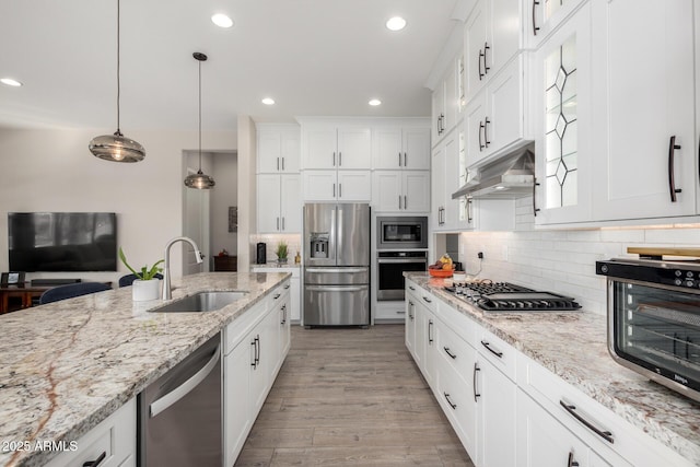 kitchen featuring white cabinetry, sink, light stone countertops, decorative light fixtures, and appliances with stainless steel finishes