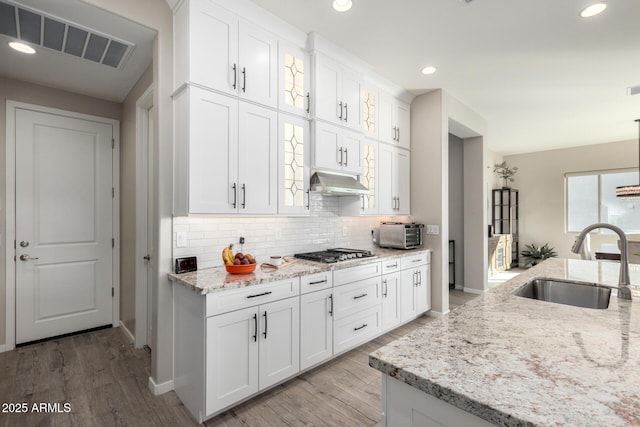 kitchen featuring extractor fan, white cabinetry, light stone countertops, and sink