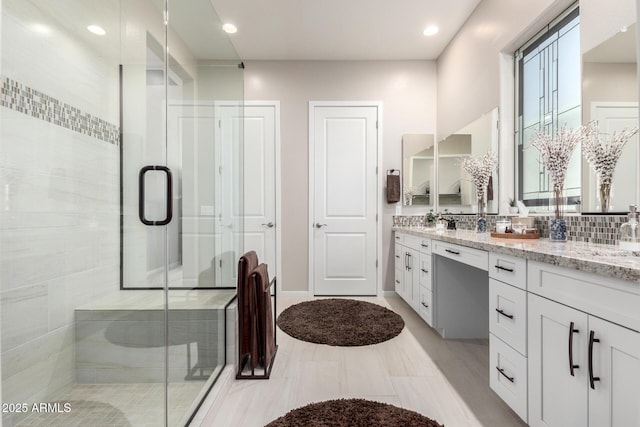 bathroom featuring vanity, tasteful backsplash, and a shower with shower door