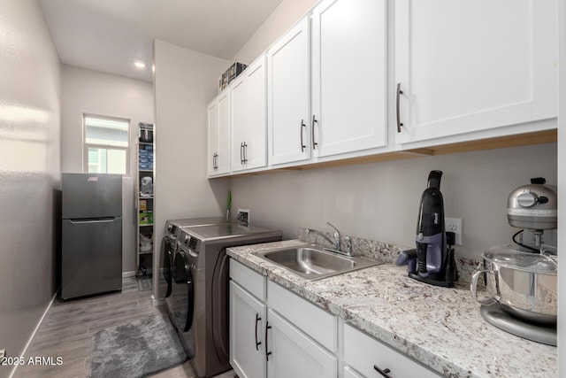 laundry area featuring cabinets, light hardwood / wood-style floors, washer and clothes dryer, and sink