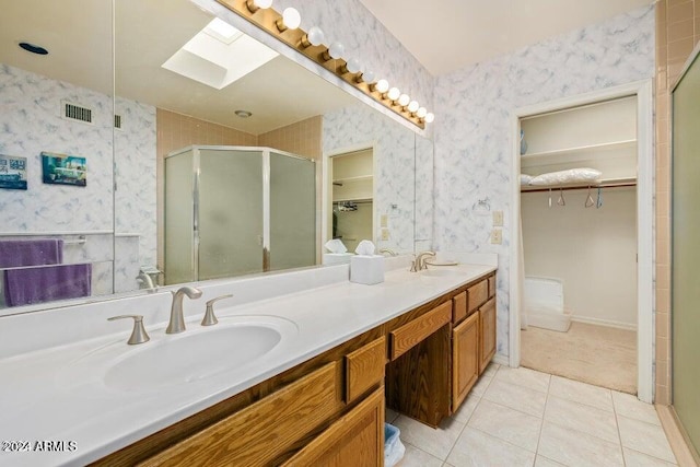 bathroom with tile patterned flooring, vanity, an enclosed shower, and a skylight