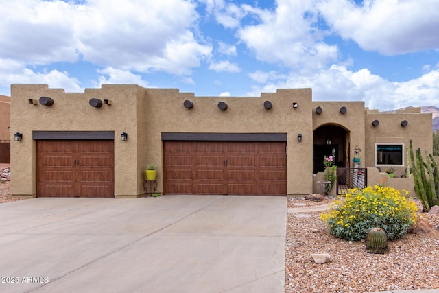 adobe home with concrete driveway, stucco siding, and an attached garage