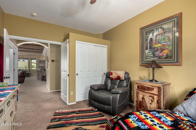 carpeted bedroom with a closet, baseboards, and arched walkways