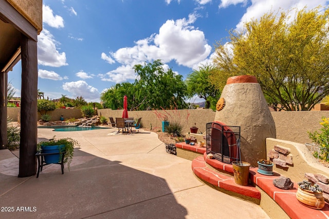 view of patio with an outdoor stone fireplace, outdoor dining area, a fenced in pool, and a fenced backyard