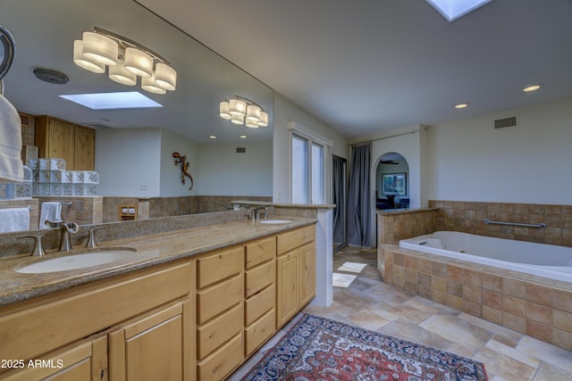 1401 E Boulder Pass, Carefree, AZ 85377 - full bath featuring a sink, stone finish flooring, a skylight, visible vents, and a bath