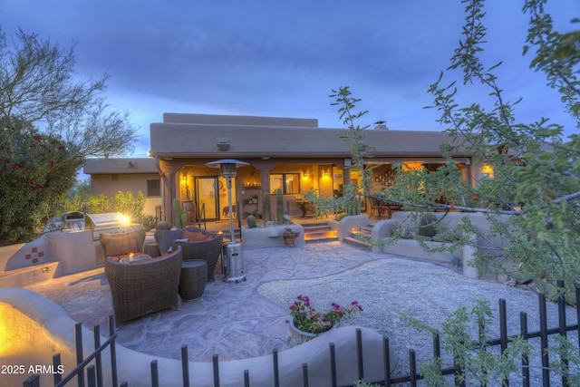 1401 E Boulder Pass, Carefree, AZ 85377 - back of house at dusk featuring stucco siding, an outdoor fire pit, a patio area, and an outdoor kitchen